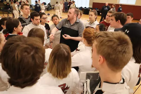 Fencing head coach Brendan Doris-Pierce huddles with the team.