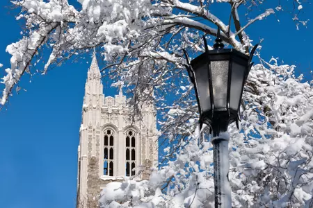 Gasson Hall in the background of a lamp post, covered in snow.