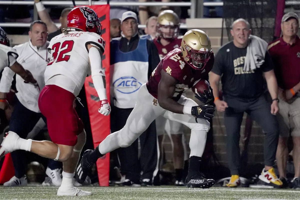 Boston College running back Pat Garwo III (24) races up the sideline as North Carolina State linebacker Drake Thomas (32) pursues during the first half of an NCAA college football game, Saturday, Oct. 16, 2021, in Boston. (AP Photo/Mary Schwalm)