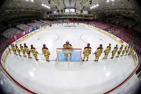 The women's hockey team stands along the goal line during pre-game introductions.