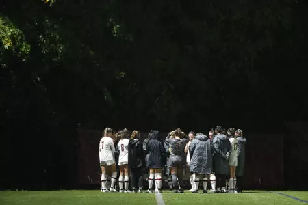 The women's soccer team hudddles at halftime in the rain.