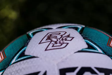 A BC-branded soccer ball sits on the turf.