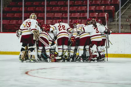 The women's hockey team huddles at the goal before a game.