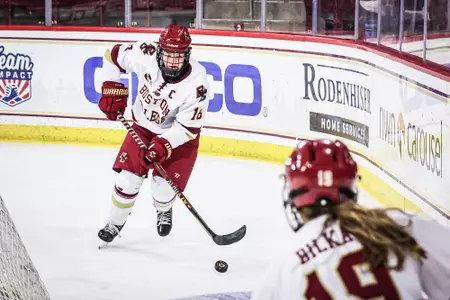 Kelly browne looks to pass the puck to Hannah Bilka behind the net.