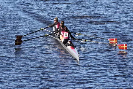 A four-person Boston College rowing boat competes on the Charles River.