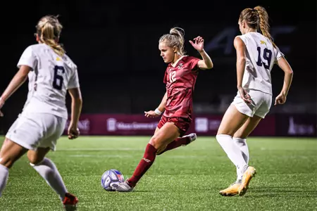 Riley Kerber looks to kick the ball with her right foot as two Michigan players close in.