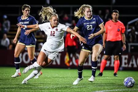 Riley Kerber dribbles the ball between two Notre Dame players.