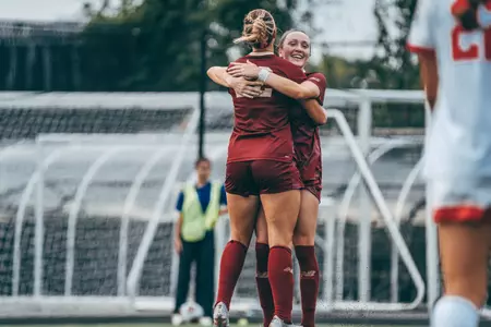 Ella Richards and Sam Smith hug, celebrating a goal against BU.