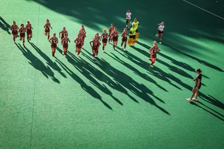 Field Hockey team running off field towards coach