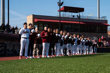 BC baseball players and coaches line up on the first base line for the National Anthem vs. Sacred Heart