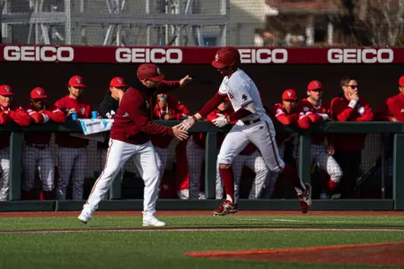Travis Honeyman high-fives third base coach Tyler Holt rounding the bases on a home run vs. NC State