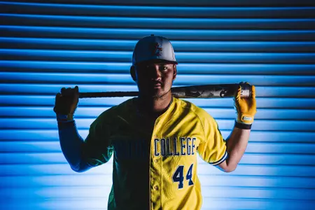Nick Wang poses with bat behind his shoulders in a yellow and blue, Boston Marathon themed jersey.