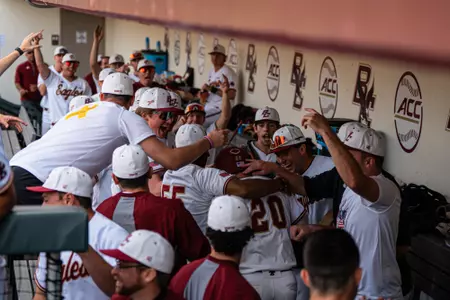 Eagle players surround Barry Walsh as he runs through the dugout after scoring vs. Duke