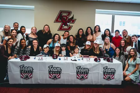 The BC women's soccer team smiles with their new teammate, Anya, at her signing day.