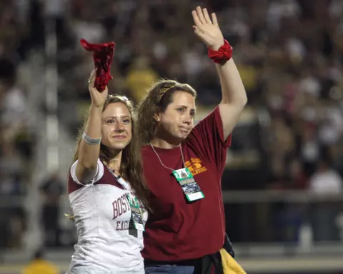 Two women wave on the field at UCF prior to the Red Bandanna game.