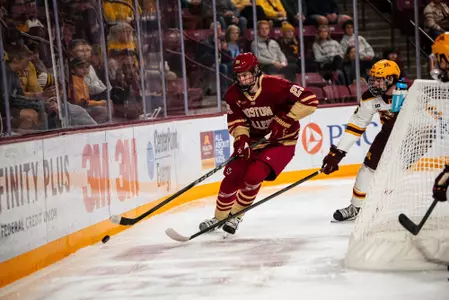 Dean Letourneau skating with the puck along the boards against Minnesota