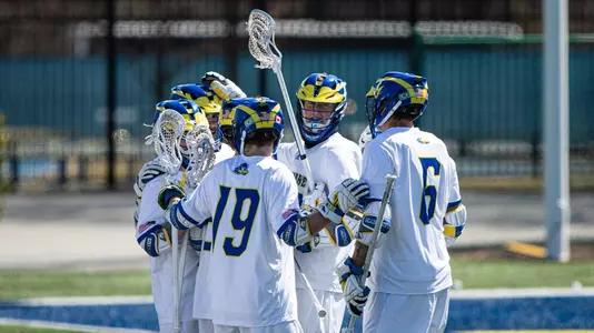 Men's lacrosse huddles after a goal in a home win against Towson