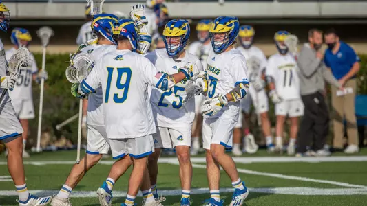 Four Blue Hens' men's lacrosse players celebrate after scoring a goal against UMass