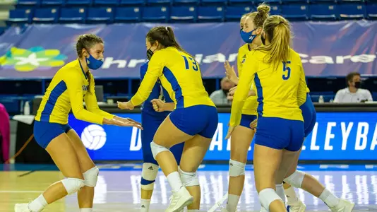 Volleyball team celebrates after scoring a point against West Virginia