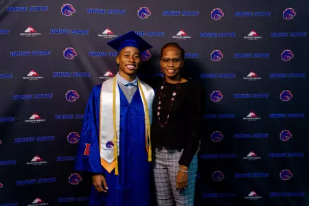 David Pierce poses in his graduation regalia with a family member.