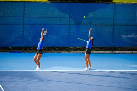 Women's tennis players hitting a serve at practice