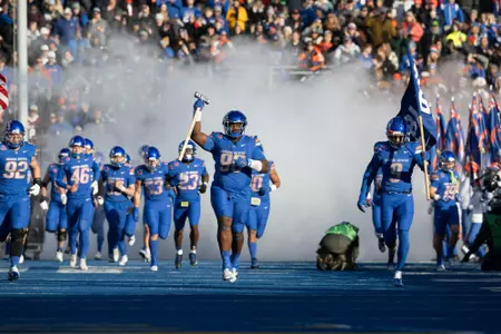Herbert Gums leads Boise State on the field with the Dan Paul Hammer