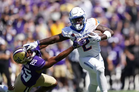 Football player stiff-arms defender