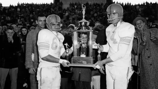 Co-captains Harry Kealoha (left) and Darrell Vail holding the National Junior College Athletics Association (NJCAA) championship trophy which the Boise football team won on Thanksgiving after defeating the Tyler (Texas) Apaches, 22-0. The team won all 10 of their games that season, and were ranked first in the NJCAA.