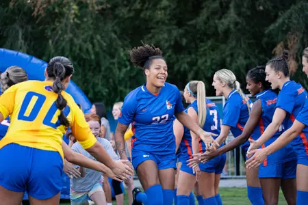 Michaela Justiniani running through a line of her teammates giving high-fives.