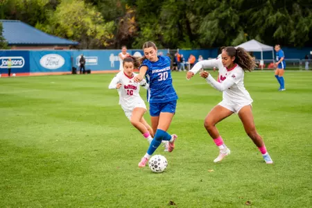 Cindy Conner, in a blue jersey, takes a run as she gets past two Bulldogs.