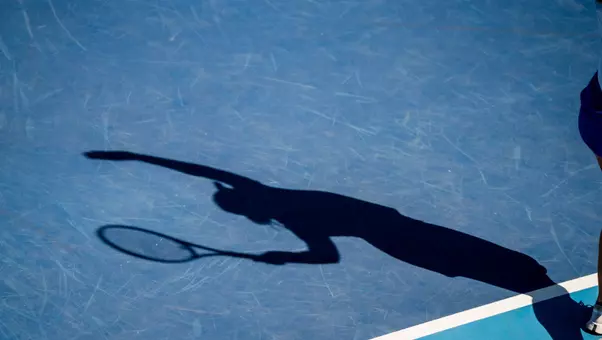 Shadow of a tennis player about to serve