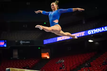 Kristina Shchennikova doing a split jump on beam.