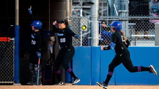 Brooklynn Pettis and Sydney Groves (background) celebrate as Mykenzie Hanna (right) runs to first base after hitting a home run.