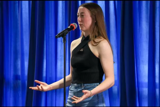 Elle Cotton in front of a microphone speaking.