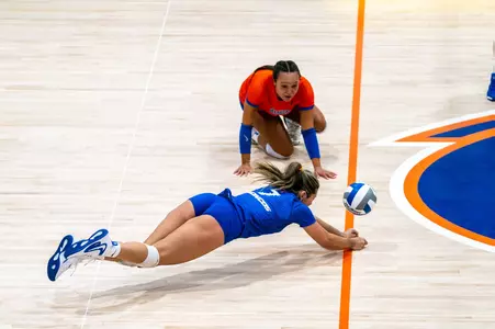 Bridey O'Connor, wearing a blue jersey and shorts, dives for the dig during the Blue-Orange Scrimmage on August 14, 2025. Bre Mitchell, in her orange libero uniform, watches in the background.