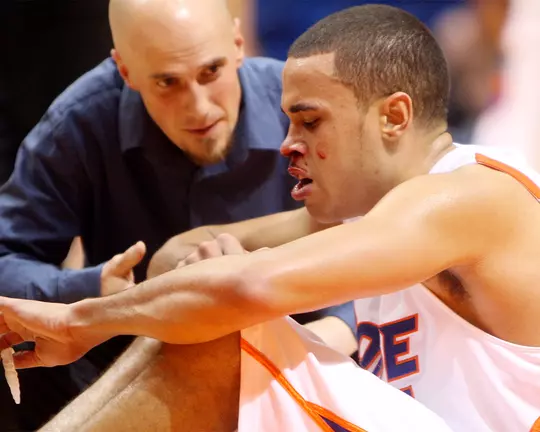 Tyler Smith treating a men's basketball player with a bloody nose