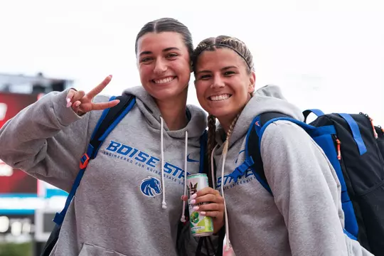 Cindy Conner and Kenzie MacMillan wearing gray Boise State sweatshirts pose for a shot while traveling to a match.