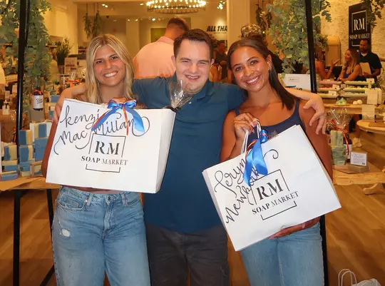 Kenzie MacMillan, Joey, Teryn Newkirk pose for a shot will the soccer team was visiting RM Soap Market.