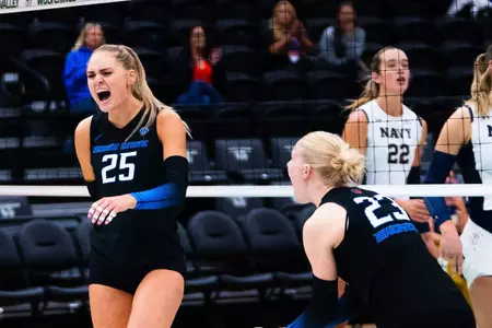 Eliza Sharp and Giselle Paedon, wearing black uniforms, with big smiles, celebrate a point during the win over Navy.