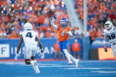 Maddux Madsen throwing a pass over a Utah State player