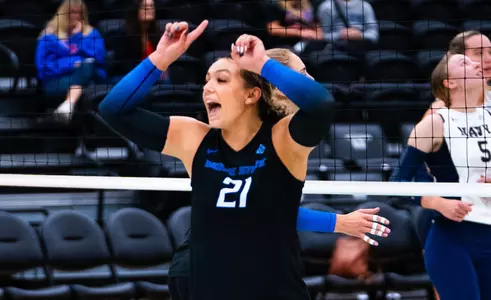 Kailyn Jager, wearing black jersey, celebrates a point in the Navy match.