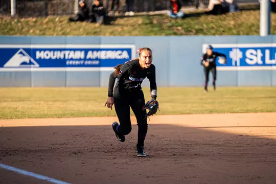 Hollie Farmer charging toward home plate from her third base position.