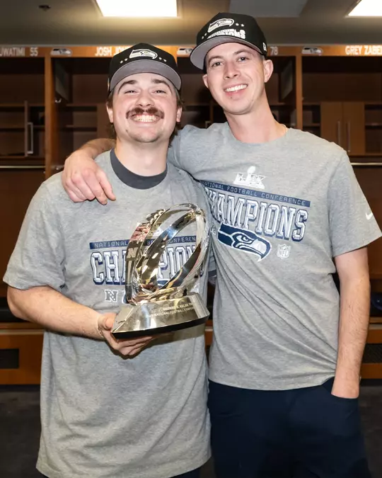 Easton Hudson (left) and Doug DeKerchove (right) holding the NFC Championship trophy