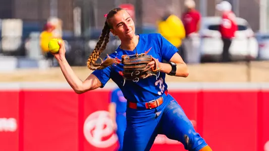 Hollie Farmer in the act of throwing a ball to first base from her third base position.