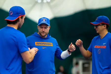 Boise State men's tennis head coach Luke Shields fist bumping Carson Baker and Avery Tallakson.