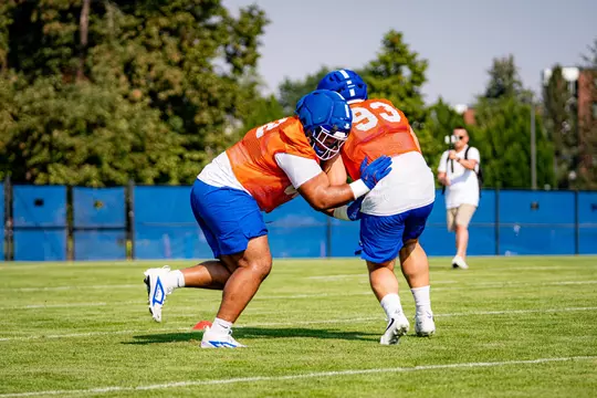 Two linemen engage in 1-on-1 blocking drill.