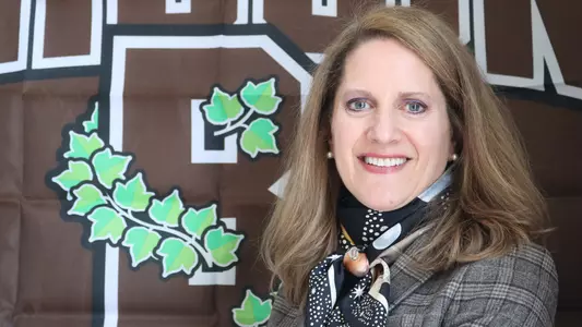 M. Grace Calhoun '92 poses in front of a Brown Athletics banner upon her hiring as director of athletics