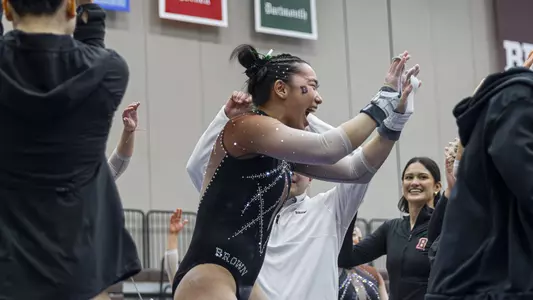 Sophia Dewar celebrates on bars against SUNY Cortland