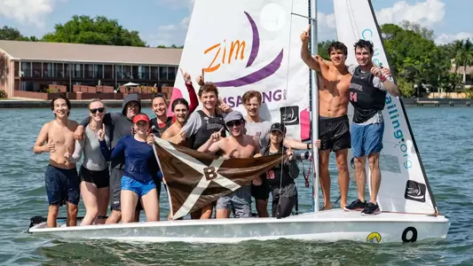 The Brown open sailing team posts with the team flag after winning the College Sailing Open Fleet Race National Championship