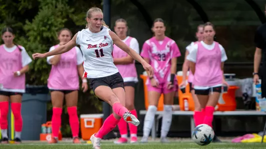 Ainsley Schaufele in a white Ball State soccer jersey kicking a soccer ball
